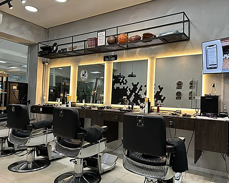 Salão da barbearia com três cadeiras e espelhos iluminados